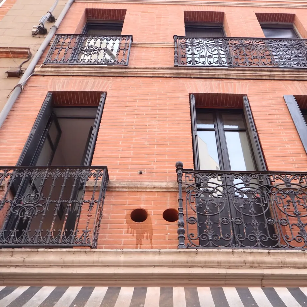 Les deux carottages vus de la rue, entre les balcons d’une façade en brique
