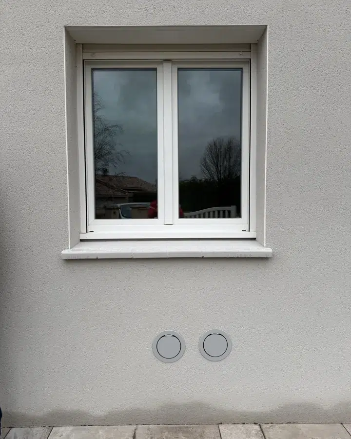 Grilles OPTIMEA standard, non peintes, sur une façade grise
