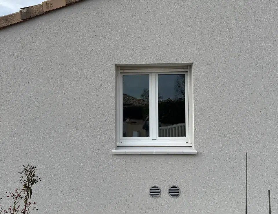 Façade d’une maison équipée par ATM Monoclim, seules deux grilles rondes visibles sous la fenêtre