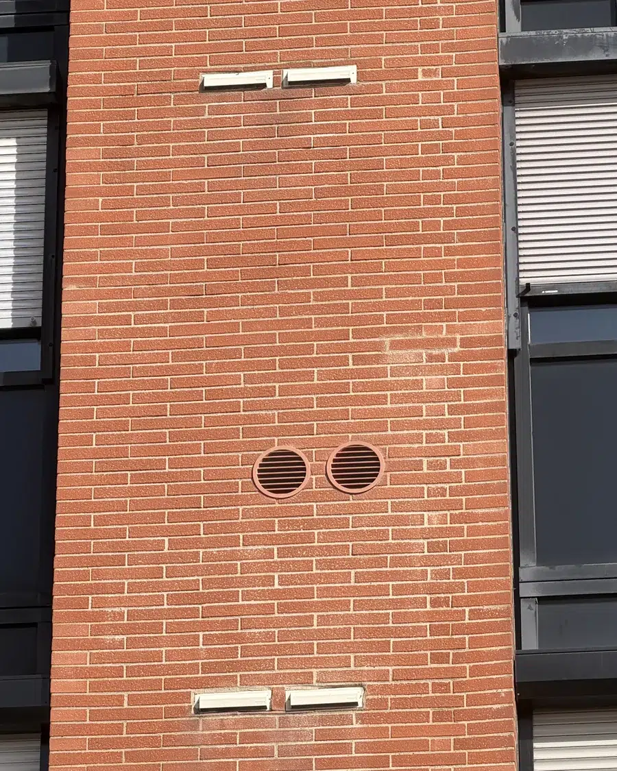 Grilles de finition extérieures à ailettes en alu (en option), peintes couleur terre cuite sur une façade imitation brique toulousaine