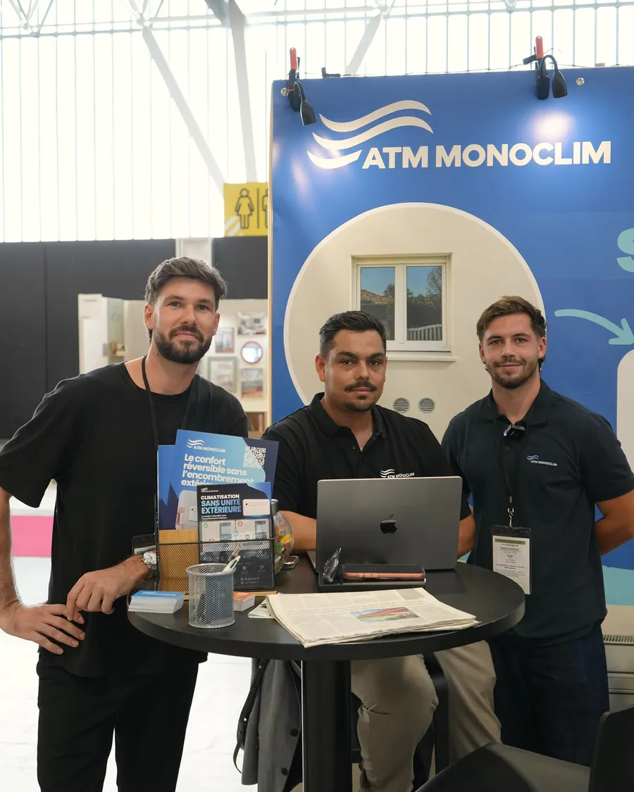 Sofiane Guitoune avec deux associés d’ATM Monoclim autour d’une table du stand, ordinateur et brochure ouverts